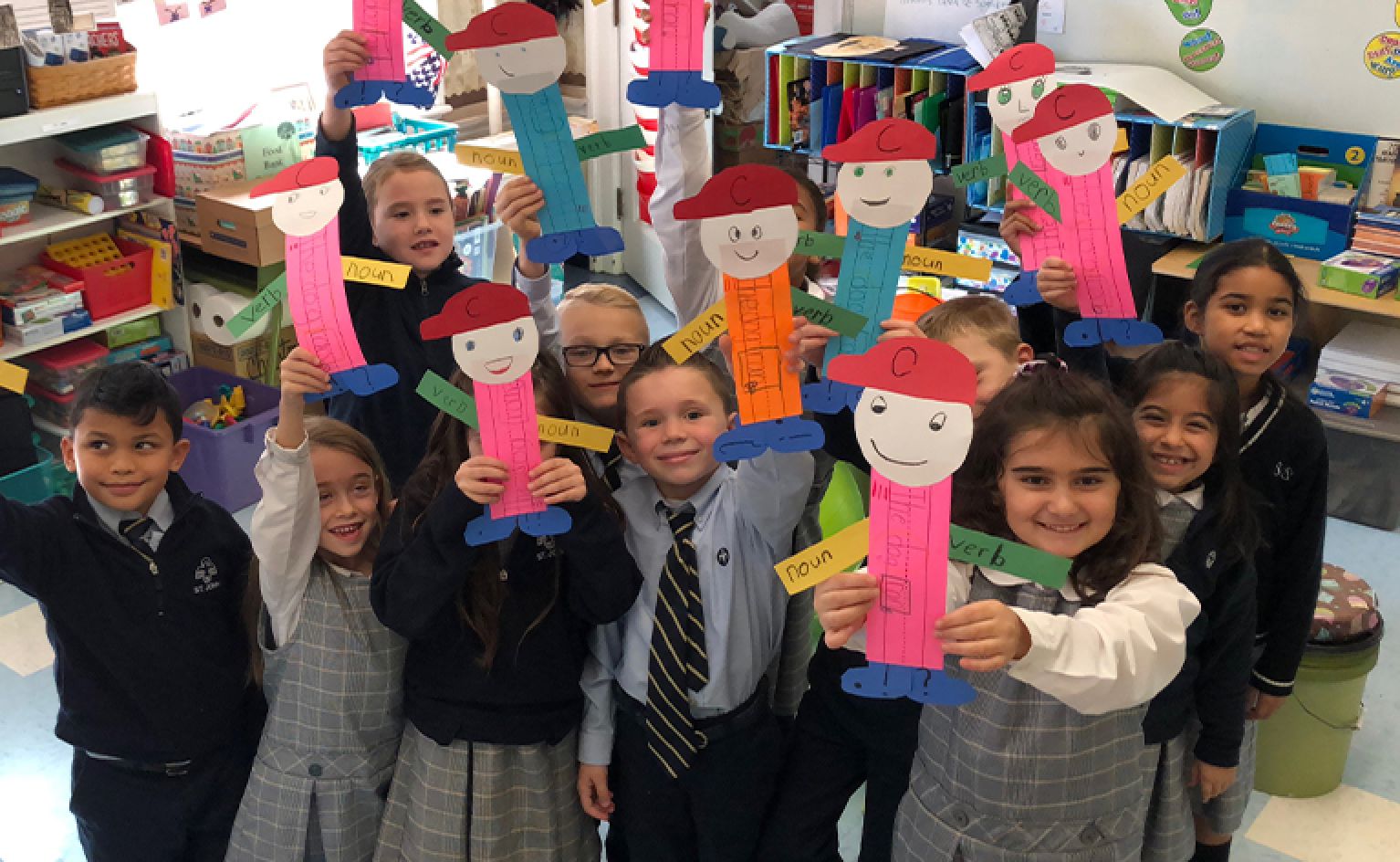 Young St. John students holding up paper made figures while learning vocabulary in the classroom
